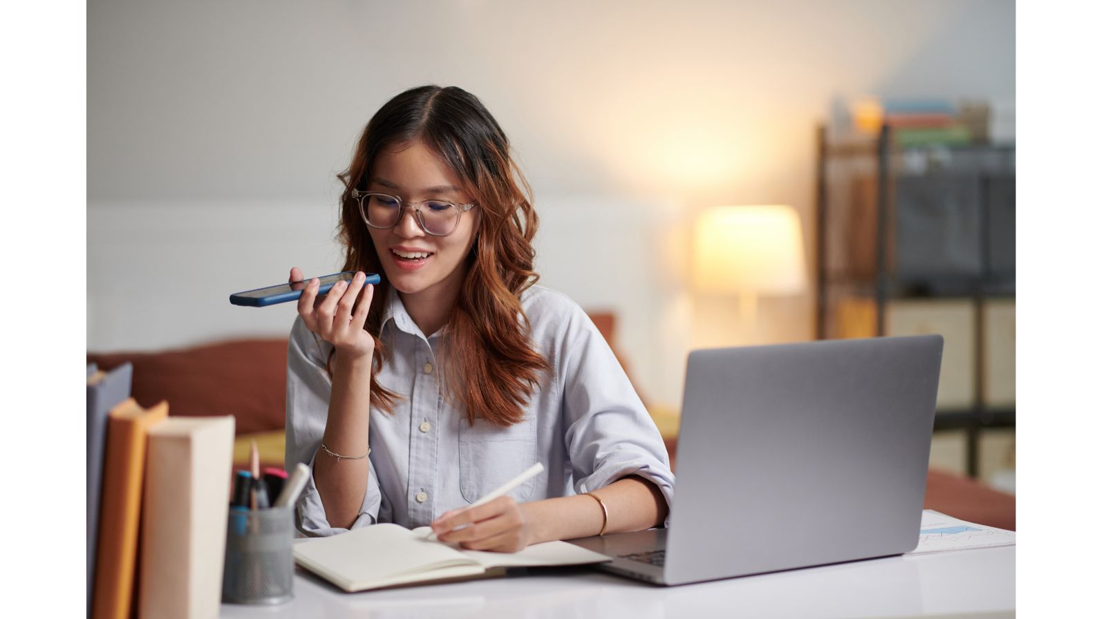 Professionista che registra un messaggio vocale mentre prende appunti al laptop, tecnica di microlearning per allenare il Business English.