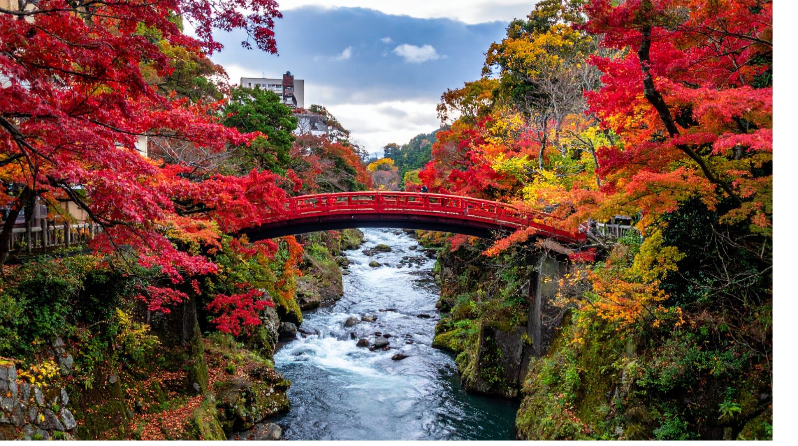Ponte rosso su un fiume circondato da alberi autunnali, metafora di prepararsi a intervenire con frasi-ponte.