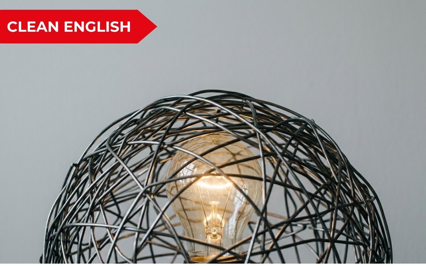 Lampadina accesa intrappolata in una struttura metallica intrecciata, metafora del perfezionismo che genera blocco mentale nel Business English.