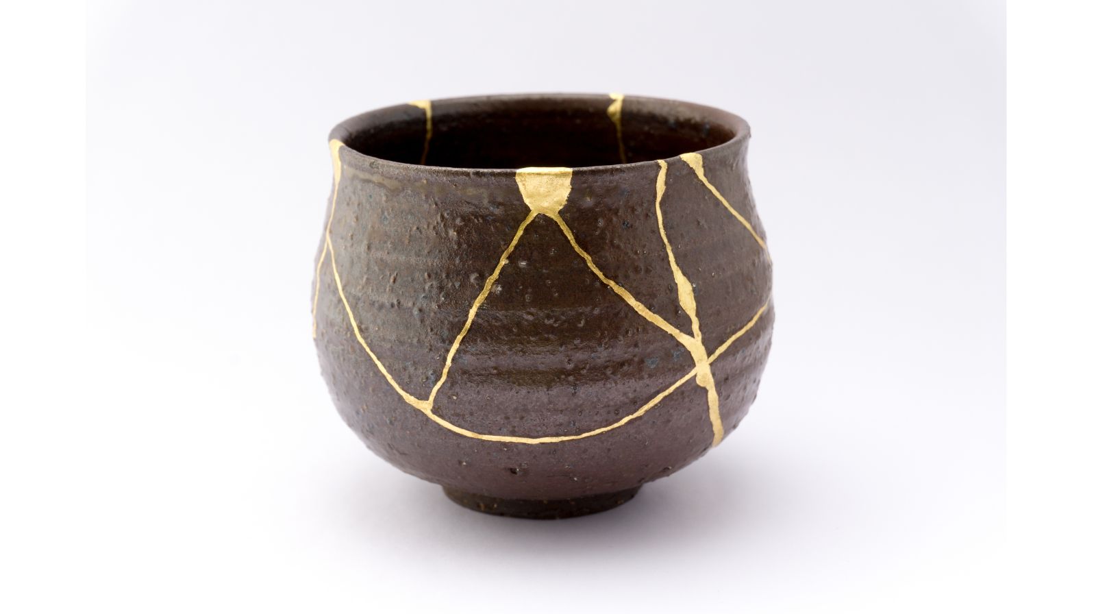 Tazza in stile kintsugi con crepe dorate visibili, metafora dell’imperfezione accettabile nella comunicazione in inglese a fronte di chiarezza ed efficacia.