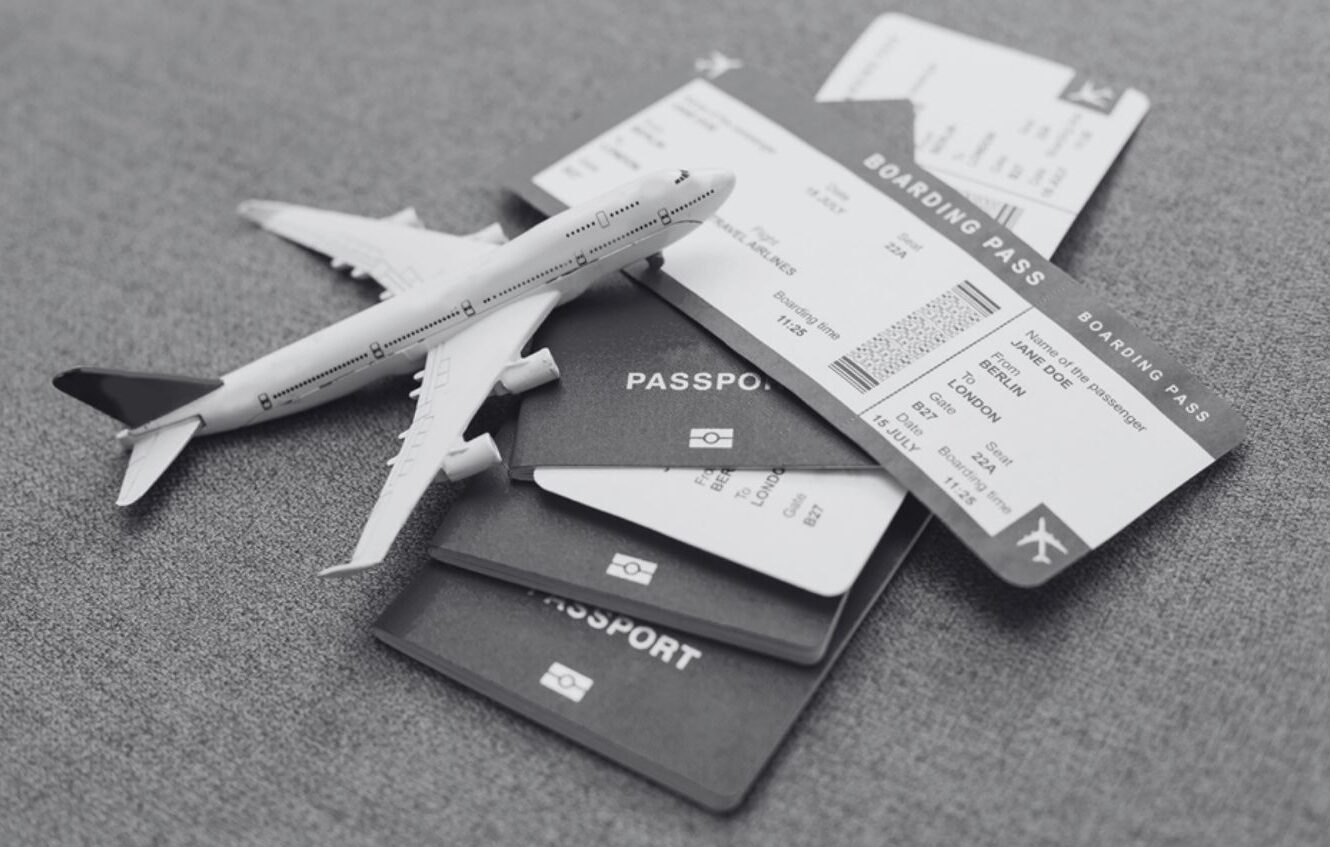 Passaporti, biglietti d'imbarco e un modellino di aereo su sfondo grigio, ideali per illustrare l'inglese per viaggiare e le trasferte di lavoro.