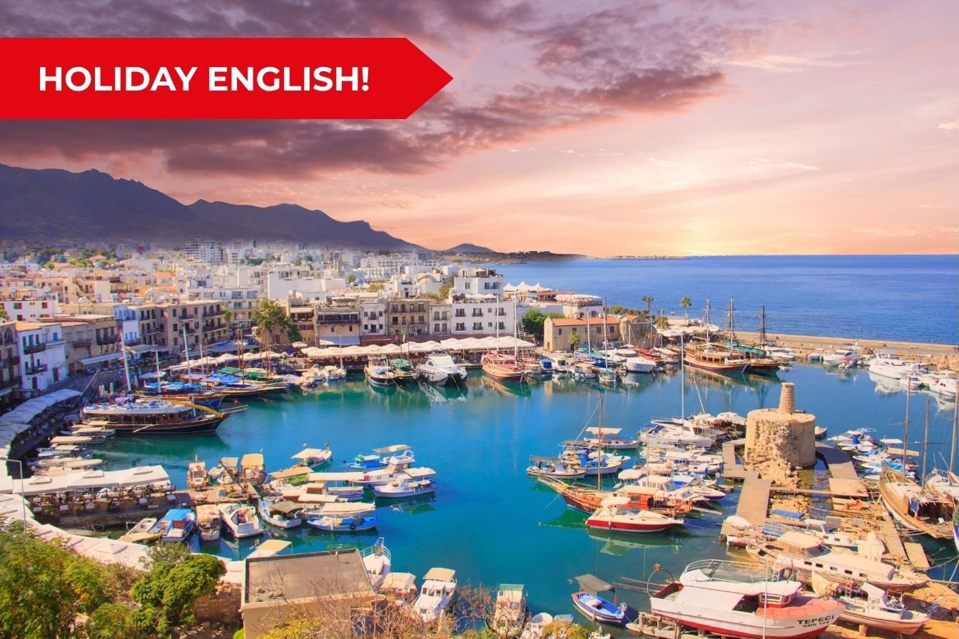 Porto turistico di Kyrenia a Cipro con barche ormeggiate al tramonto, banner rosso in alto a sinistra e testo Holiday English per l'articolo del blog.