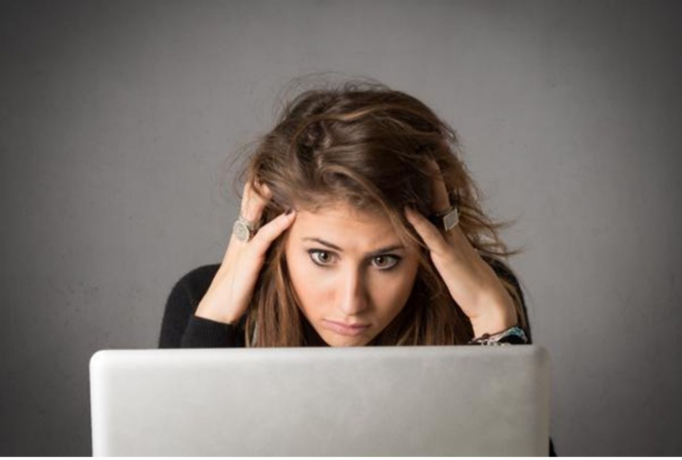 Primo piano di una professionista sopraffatta dallo stress lavorativo e dal sovraccarico di impegni al computer.